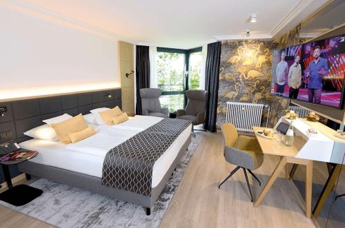 a hotel room with a large bed and a desk at FAVORITE Parkhotel in Mainz