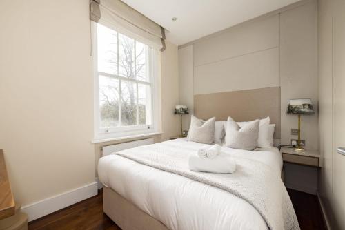 um quarto com uma cama branca com uma toalha branca em Light-filled Chelsea Duplex em Londres