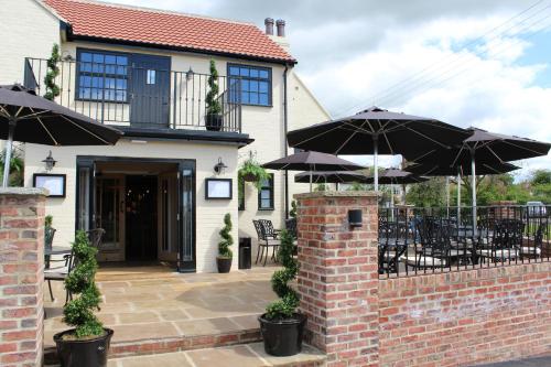 a patio with tables and umbrellas in front of a house at The Blue Bell at Arkendale in Knaresborough