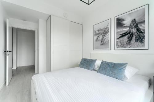a white bedroom with a bed and pictures on the wall at Shellter City Apartments in Rogowo
