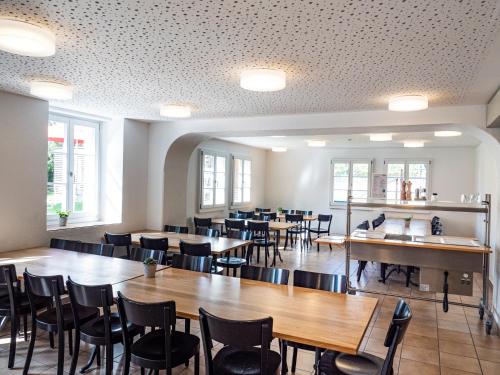 a dining room with tables and chairs and windows at Avenches Youth Hostel in Avenches