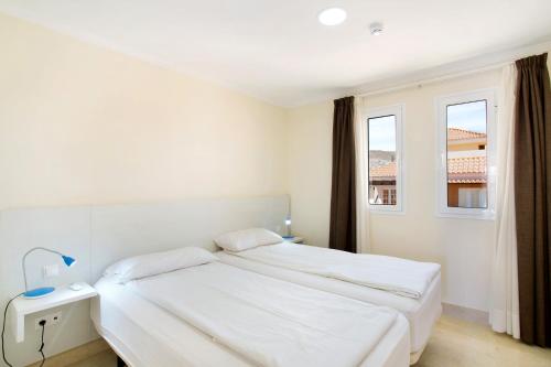 een witte slaapkamer met een bed en 2 ramen bij Pineda H in Arguineguín