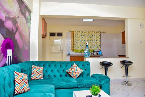a living room with a blue couch and a kitchen at DESIRED 2 BEDROOM Apartment in Thika