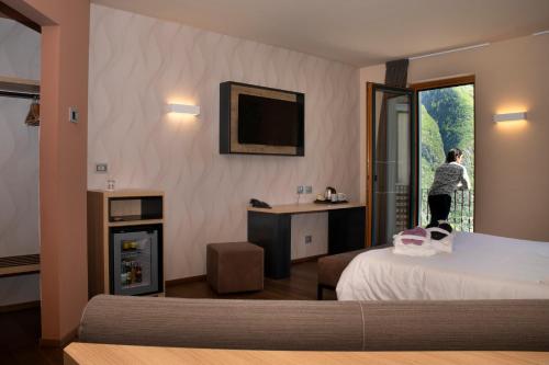 ein Hotelzimmer mit einem Bett und einer Frau aus dem Fenster in der Unterkunft Belvedere Hotel in Crodo