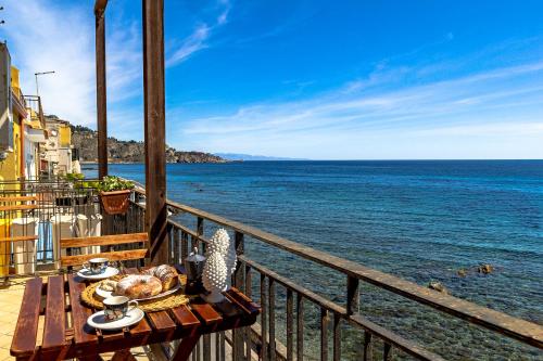 einen Tisch mit Speisen auf einem Balkon mit Meerblick in der Unterkunft Acquamarina Home in Giardini-Naxos