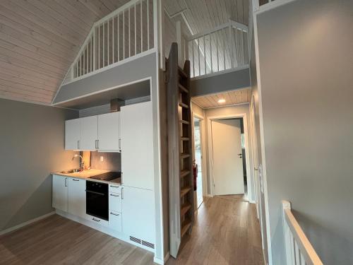 a kitchen with white cabinets and a loft bed at Rorbu i Bud Havn in Bud