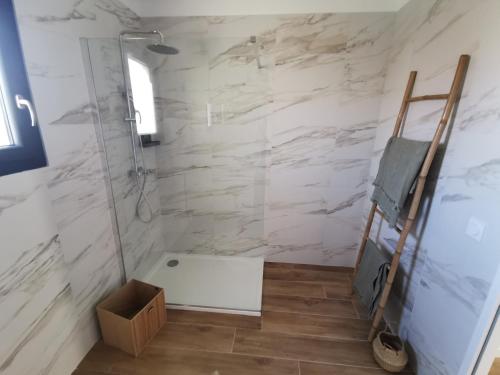 a bathroom with a shower with white marble walls at Résidence Petra Paolina in Folelli