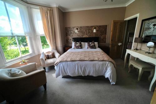 a bedroom with a bed and a chair and windows at Cannara B and B in Great Malvern