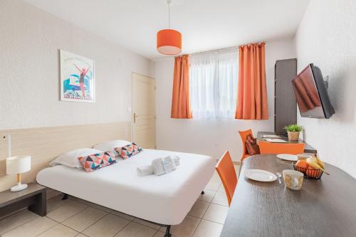 a bedroom with a white bed and a table at Appart'City Classic Marseille Aéroport - Vitrolles in Vitrolles