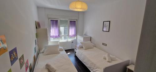 um quarto com duas camas e duas janelas em Astur Playa I - WiFi · 2 Hab · 2 Baños · 4 pax em Gijón