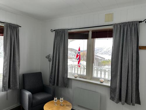 a room with a chair and a window with a flag at Storfossen Hostel in Gratangen