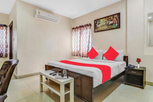 a hotel room with a large bed with red pillows at Hotel Airport Shine Inn in Shamshabad