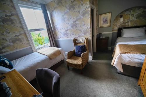 a bedroom with two beds and a chair and a window at Cannara B and B in Great Malvern