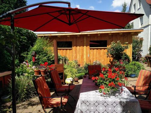 a red umbrella on a patio with a table with flowers at Neckar-Koje in Neckarsulm