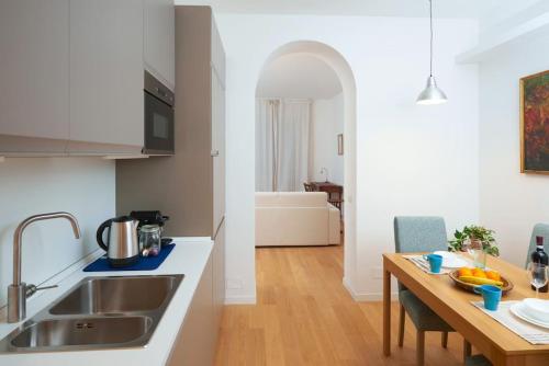 a kitchen with a sink and a table with a dining room at Luma Apartment Navigli: Cozy and Romantic Getaway in Milan