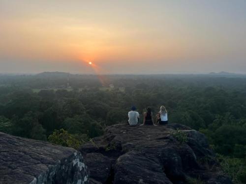 two people sitting on a rock watching the sunset at Bulnewa Grammar International home stay/Tree-house 