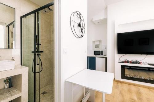 a white bathroom with a shower and a television at GuestReady - Amazing Studio near Disneyland in Montévrain