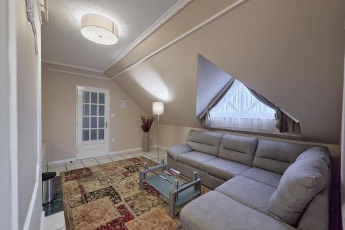 a living room with a couch and a large window at Tokajer Wellness Panzió in Keszthely