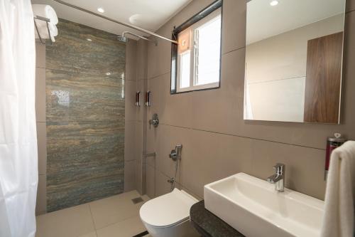a bathroom with a toilet and a sink and a shower at The Living Hub Hotel, Kolhapur- Walkable From Central Bus Station in Kolhapur