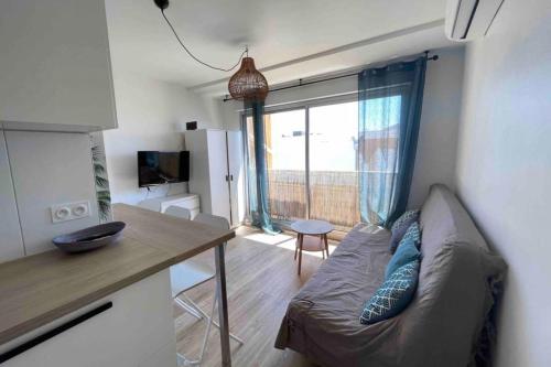 un salon avec un canapé et une cuisine avec une fenêtre dans l'établissement Studio for 4 people near the beach with air conditioning, à Palavas-les-Flots