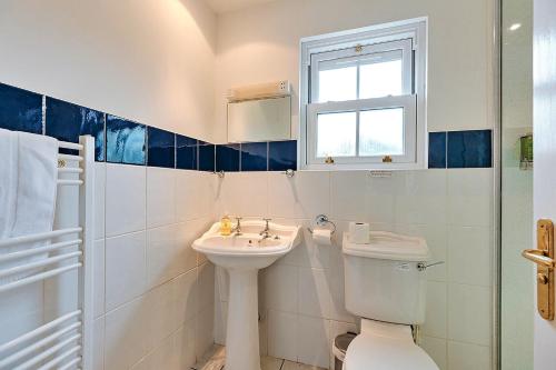 Baño blanco con aseo y lavamanos en Finest Retreats - Netley Hall - Jasmine, en Dorrington