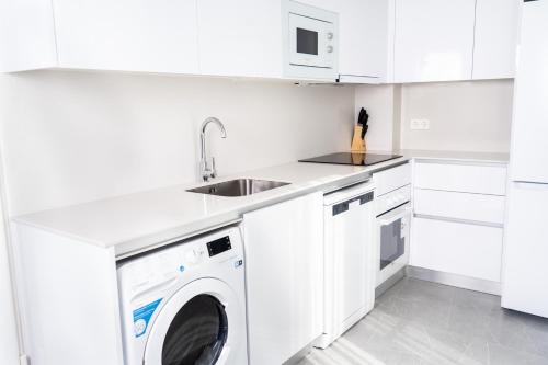 a white kitchen with a washing machine and a sink at Apartamentos Turísticos Plaza del Rey in Cartagena