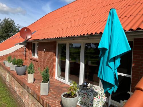 uma casa de telhado laranja com plantas e um guarda-chuva em Ferienwohnung Bruns em Ihlow