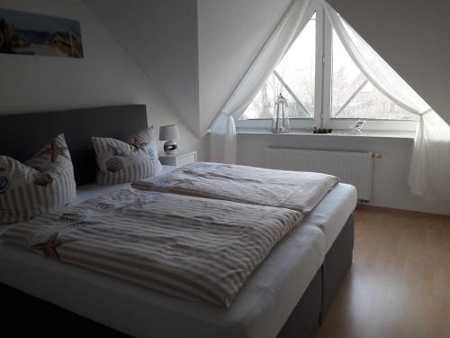 uma cama num quarto com uma grande janela em Ferienwohnung Haus Bikker em Ihlow