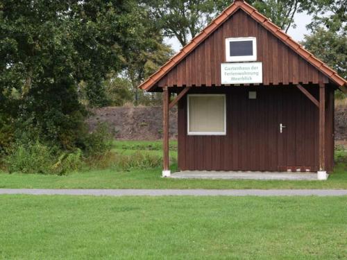 a small building with a sign on it in the grass at Ferienwohnung Meerblick in Ihlow
