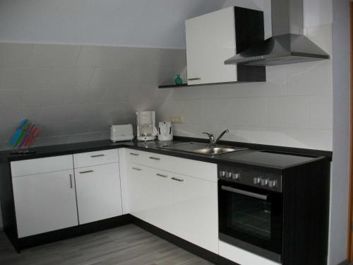 a kitchen with white cabinets and a sink and a stove at Ferienwohnung Haus Bikker in Ihlow