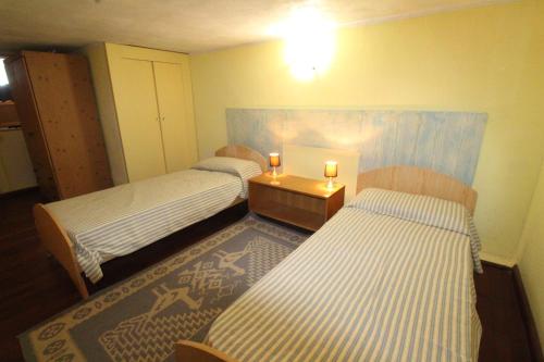 Cette chambre comprend deux lits et une table avec deux bougies. dans l'établissement Quadrilocale Tanca Manna, à Cannigione
