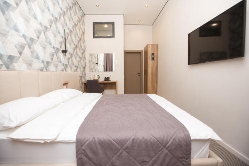 a bedroom with a bed and a flat screen tv at ASYL Hotel in Astana