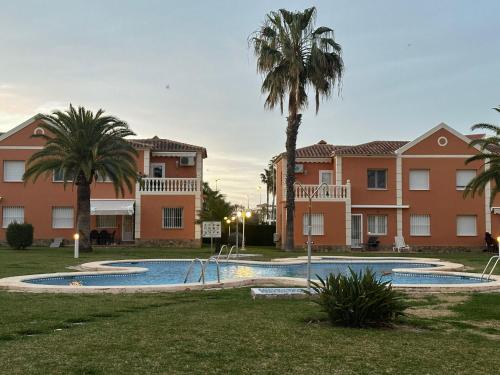 una piscina con palmeras frente a los edificios en OLIVA NOVA GOLF BEACH & RESORT Club Sevilla VI 3A, en Oliva