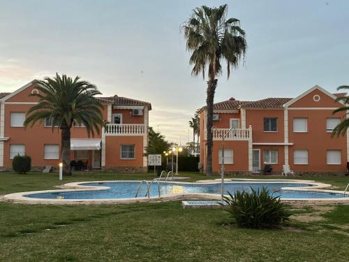 una piscina con palmeras y edificios en OLIVA NOVA GOLF BEACH & RESORT Club Sevilla VI 3A, en Oliva