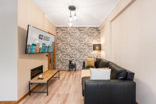 a living room with a black leather couch and a brick wall at GuestReady - A breath of fresh air in Nogueiró in Nogueiro