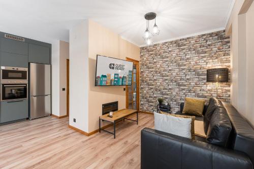 a living room with a couch and a brick wall at GuestReady - A breath of fresh air in Nogueiró in Nogueiro