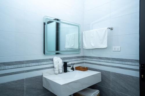 a white bathroom with a sink and a mirror at VIOLET VILLA in Hòa Bình