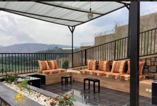 a patio with two couches and a table and a balcony at Furnished House at Kibagabaga in Kigali
