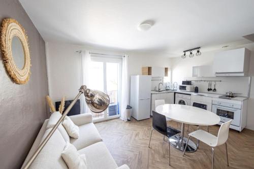 Il comprend un salon blanc avec une table et une cuisine. dans l'établissement Appartement T3 climatisé centre ville Pérols, à Pérols