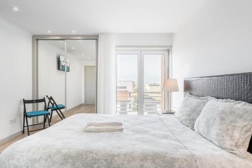 a white bedroom with a large bed and a chair at GuestReady - Vacation family home near the beach in Esposende