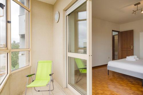 a room with green chairs and a bed and windows at GuestReady - Unwind in Ryan's Place in Braga