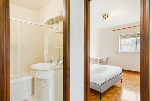 a white bathroom with a sink and a bed at GuestReady - Unwind in Ryan's Place in Braga