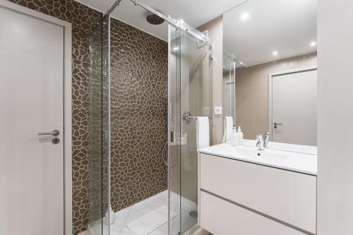 a bathroom with a glass shower and a sink at GuestReady - Vacation family home near the beach in Esposende