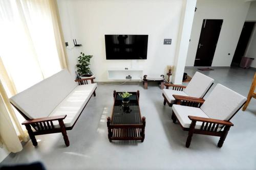 a living room with white furniture and a flat screen tv at Modern Brand New House in Palakkad