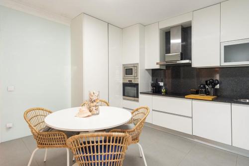 a white kitchen with a white table and chairs at GuestReady - Marinhas Beauty near Esposende Beach in Esposende