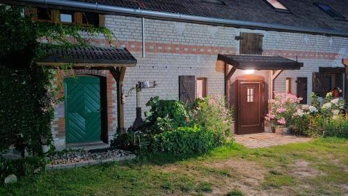 a brick house with a green door in a yard at Siedlisko Karczówka in Wieleń