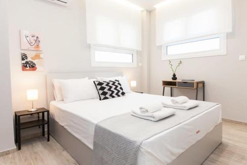 a white bedroom with a bed with two towels on it at Brand New flat near Lycabettus Hill by Luckeys in Athens