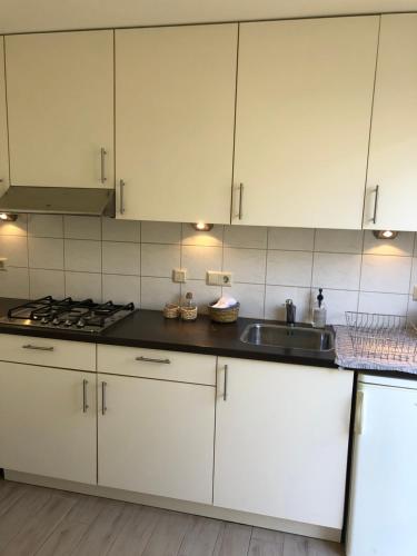a kitchen with white cabinets and a sink at Vakantiehuis in Katwijk aan zee in Katwijk aan Zee