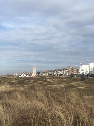 a field of grass with buildings in the background at Vakantiehuis in Katwijk aan zee in Katwijk aan Zee