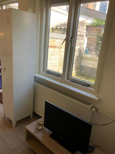 a living room with a tv and a window at Vakantiehuis in Katwijk aan zee in Katwijk aan Zee